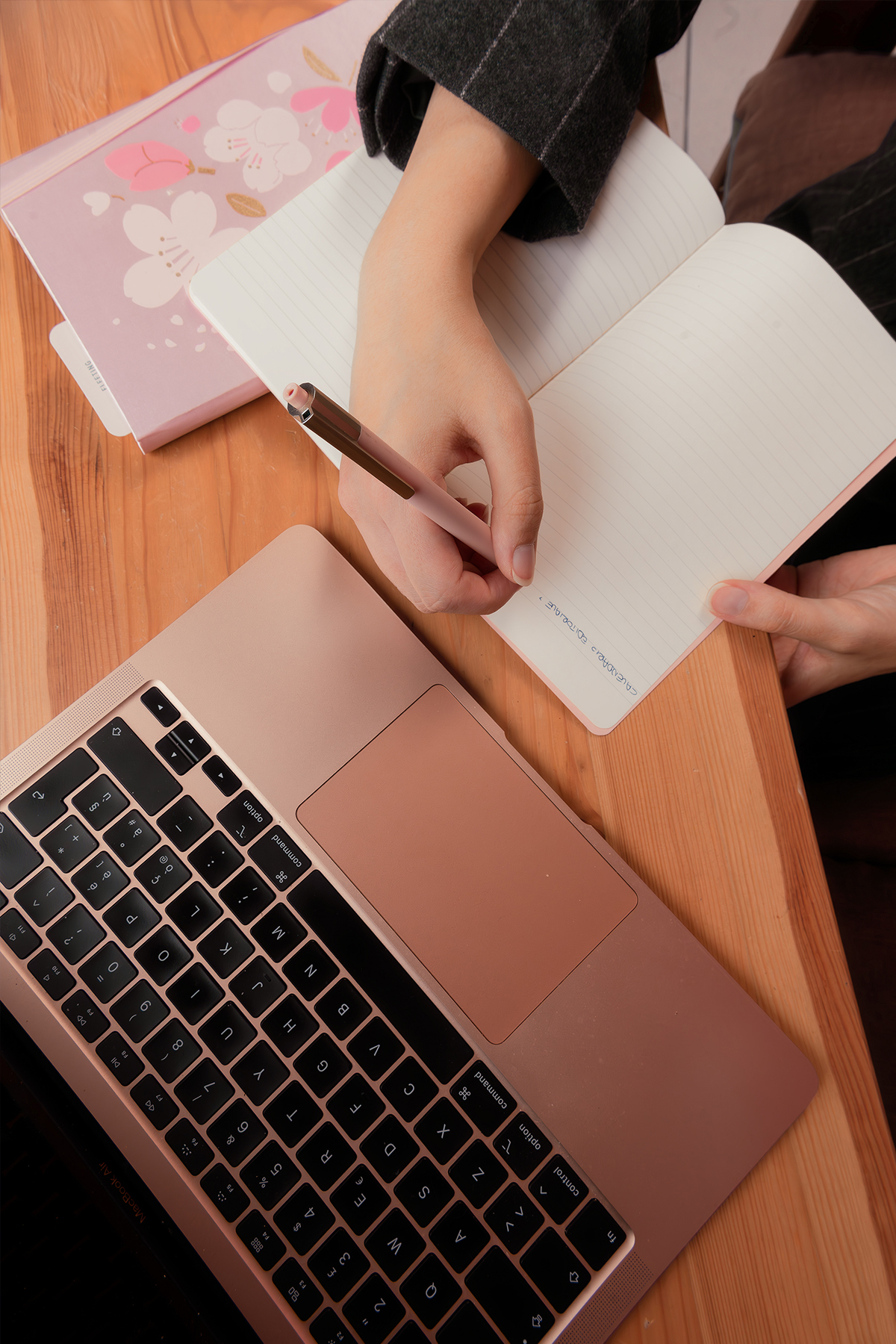 Mani su laptop e quaderno su un tavolo di legno