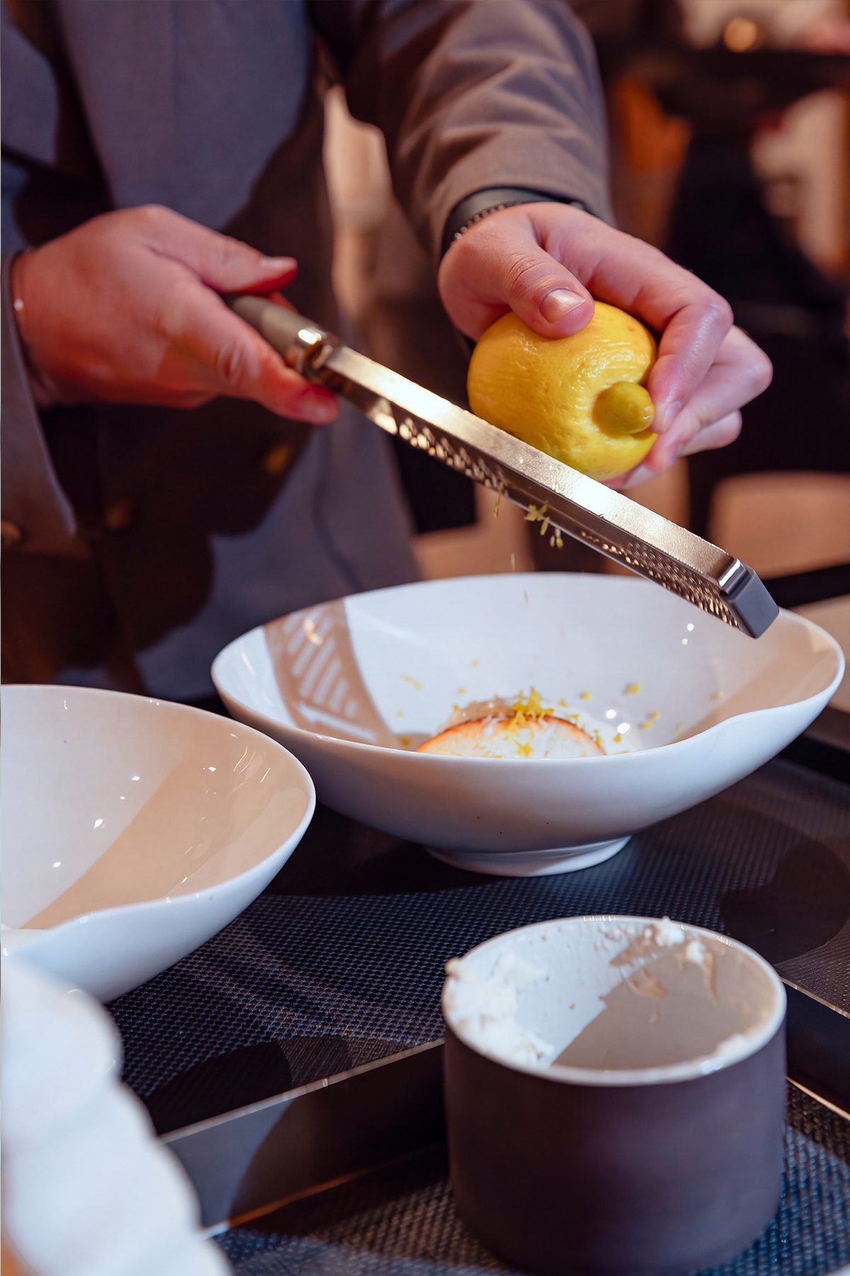 Mani che spremono un limone sopra una ciotola, servizio per ristorazione