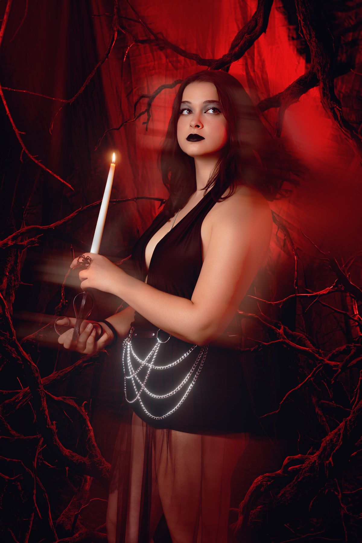 Cosplay con candela e luce rossa, rami intrecciati