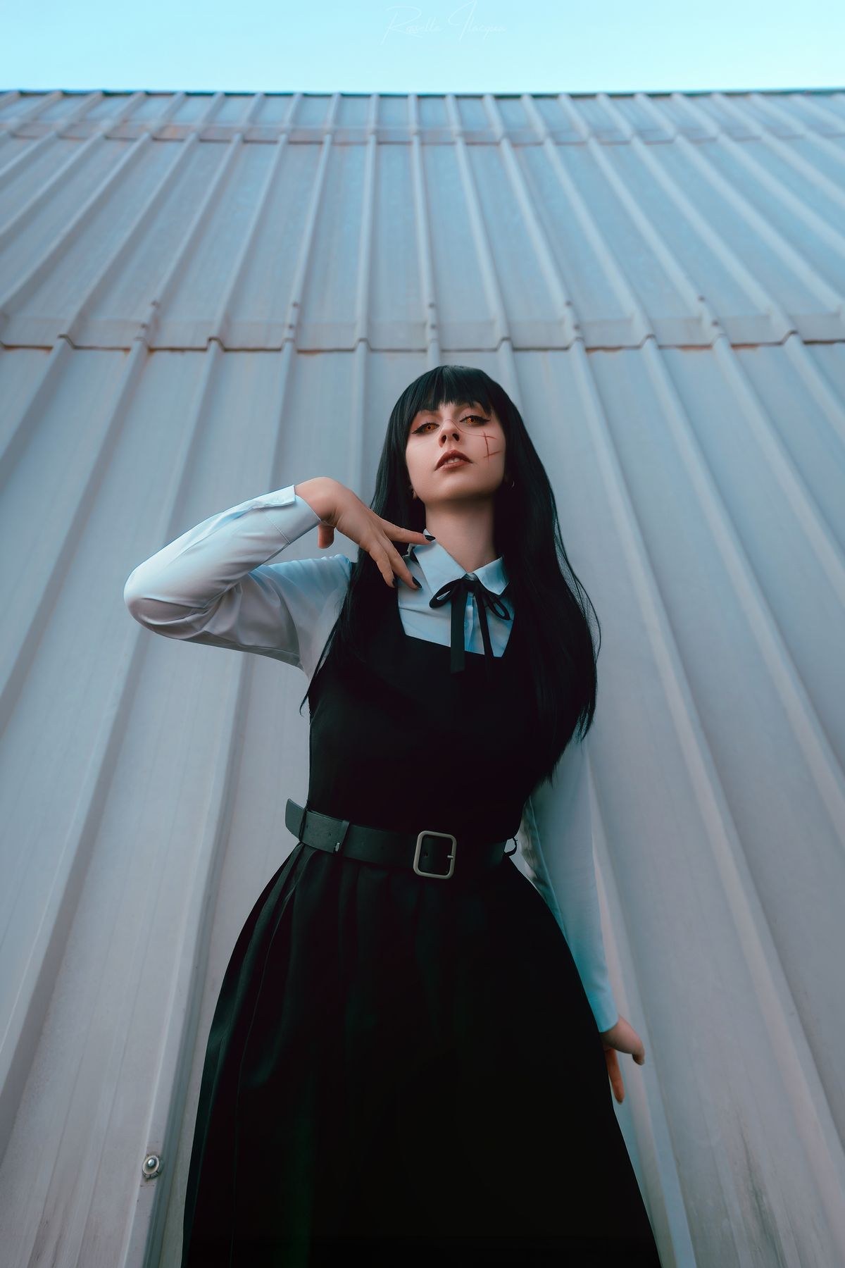 Cosplay in abito nero e camicia bianca, parete ondulata