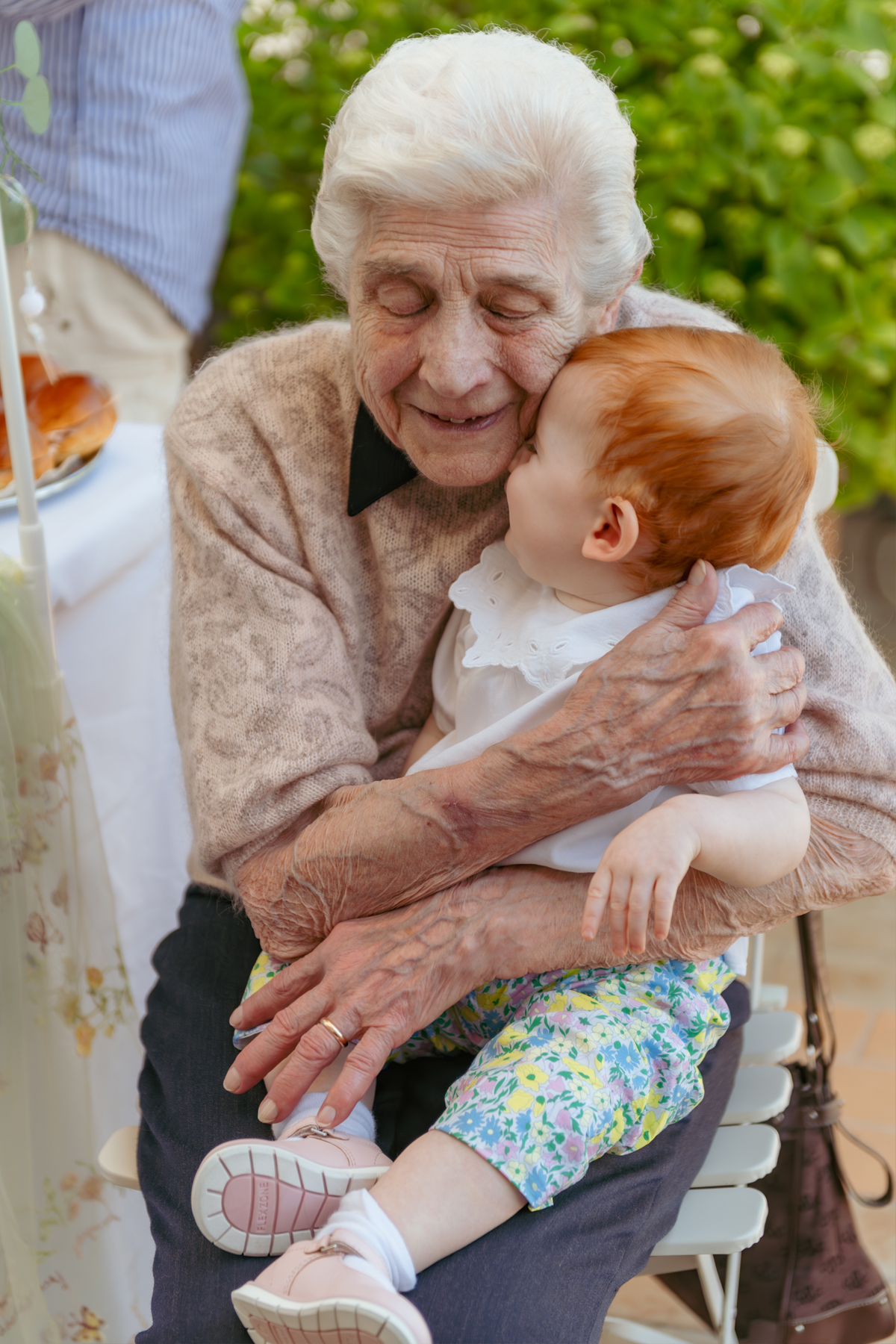 Anziana con la nipote in braccio durante una festa di famiglia