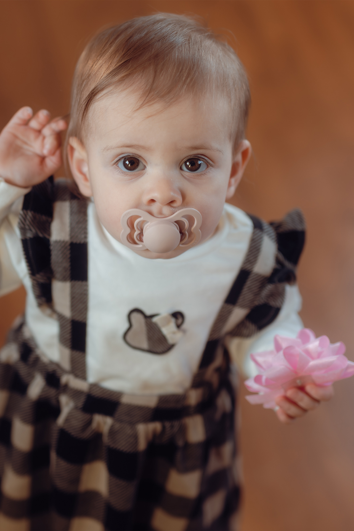 Bambina in vestitino a quadri con ciuccio
