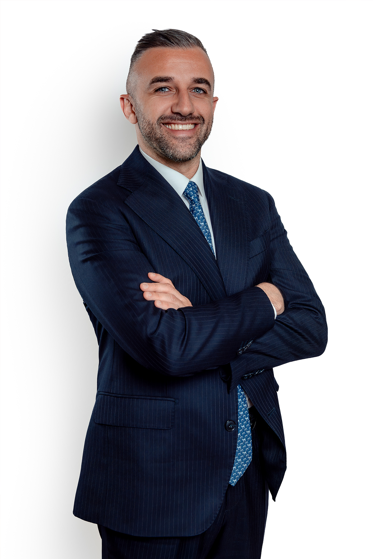 Ritratto di uomo in giacca blu, braccia conserte, su fondo bianco